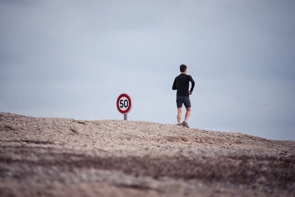 Homme en tenue de sport debout sur un rocher, de dos